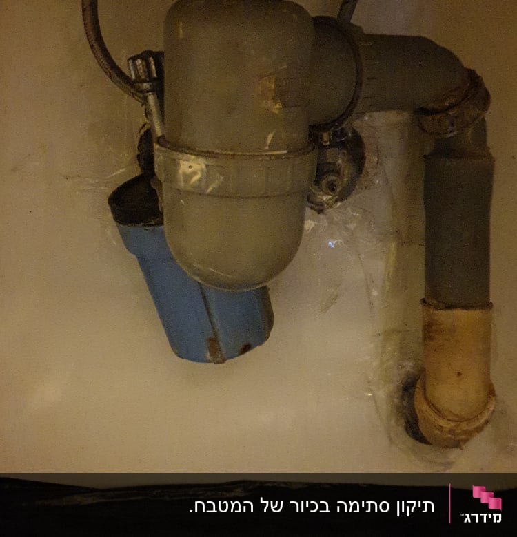 צנרת מתחת לכיור עם מסנן מים כחול